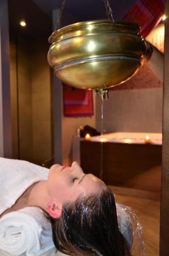 a woman laying on a bed under a bell at Hotel Azalia & Spa in Niepołomice