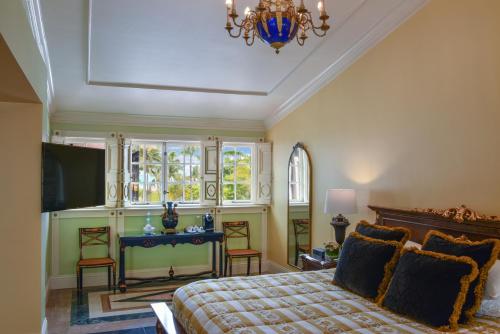 a bedroom with a bed and a television and a chandelier at The Villa Casa Casuarina in Miami Beach