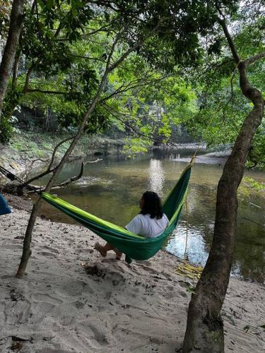 a woman sitting in a hammock next to a river at Aqeel cabin in the nature in Penonomé