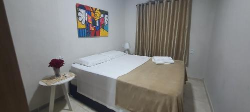a bedroom with a bed and a vase of flowers on a table at Apto 2 - Hospedagem da Almira in Manaus