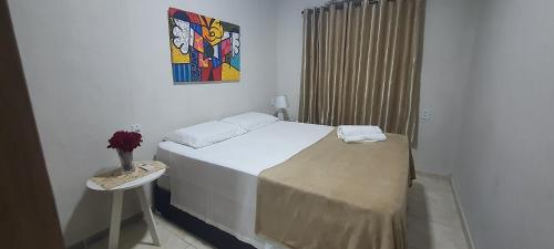 a bedroom with a bed and a vase of flowers on a table at Hospedagem da Almira - Apartamento 2 in Manaus