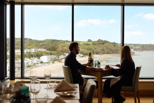 a man and woman sitting at a table in a restaurant at St Brides Spa Hotel & Village Apartments in Saundersfoot