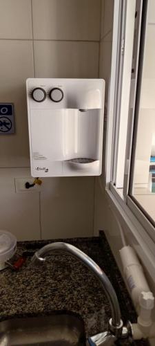 a microwave above a kitchen sink next to a window at Ap23 Cristal do Indaiá I 450m praia in Bertioga