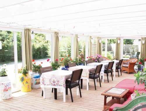 a conservatory with tables and chairs and windows at Hine Bakke Bed And Breakfast in Rudkøbing