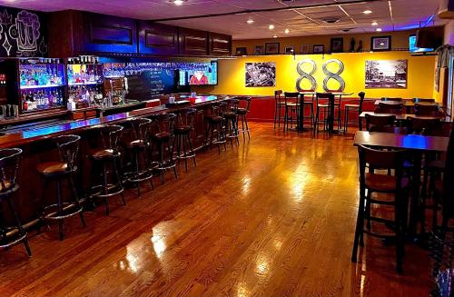 un bar con pavimenti in legno e sgabelli da bar in una stanza di Bicentennial Inn a Buckhannon