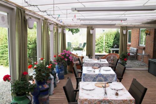 un patio con mesas y sillas con flores. en Hine Bakke Bed And Breakfast en Rudkøbing