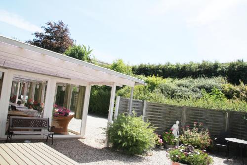 a garden with a fence and a patio at Hine Bakke Bed And Breakfast in Rudkøbing