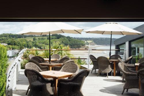 a patio with tables and chairs and umbrellas at St Brides Spa Hotel & Village Apartments in Saundersfoot