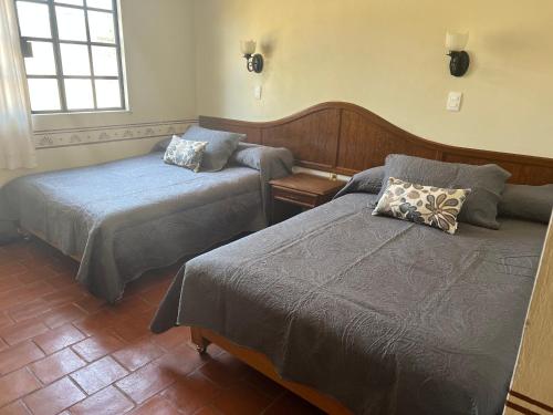 a hotel room with two beds and a window at Hotel Real de Huasca in Huasca de Ocampo