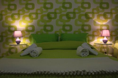 a bedroom with a green bed with two lamps at B&B Dietro l'Angolo in Benevento