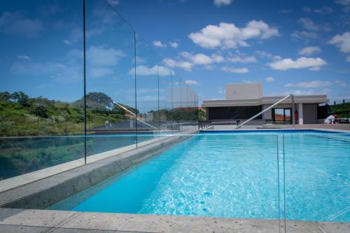 巴利托的住宿－Zimbali Lakes Boulevard Suites，一座带玻璃墙的建筑前的游泳池