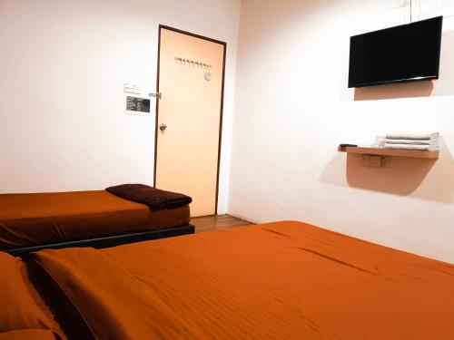 a room with two beds and a door with a television at BMW Hotel in Muar