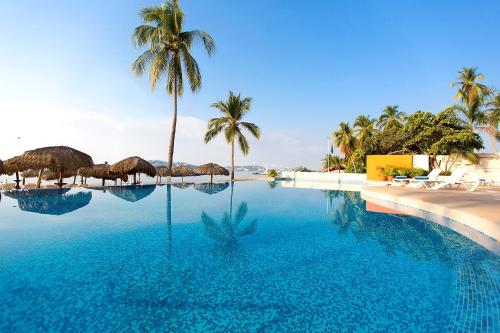 a swimming pool with palm trees and blue water at Krystal Beach Acapulco in Acapulco