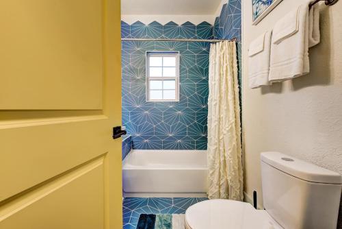 a bathroom with a tub and a toilet and a window at Color Pop Cottage - Half mile from Plaza district in Oklahoma City