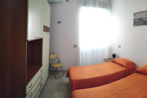 1 Schlafzimmer mit 2 Betten, einem TV und einem Fenster in der Unterkunft Casa Alea - Appartamento turistico - Paola- in Paola