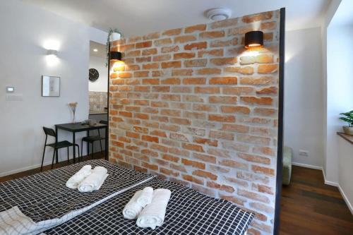 a brick wall with two pairs of white slippers on a bed at Wally apartment in Ljubljana