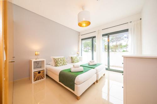 een witte slaapkamer met een bed en een groot raam bij RT Palmela Village in Palmela