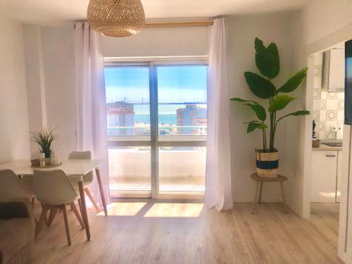 ein Wohnzimmer mit einem Tisch und einem großen Fenster in der Unterkunft Frente al mar, preciosas vistas, piscinas , valdelagrana in El Puerto de Santa María