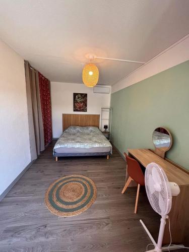 a bedroom with a bed and a desk with a fan at La Kaz Vert d’Õ in Saint-Denis