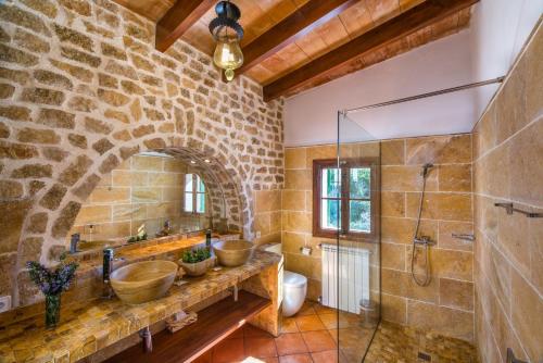 Baño de piedra con 2 lavabos y ducha en Hotel Sa Vall, en Valldemossa