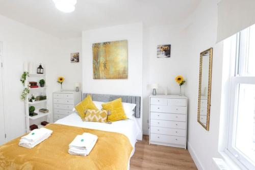 a white bedroom with a large bed with yellow pillows at King's Central Cambridge Apartment in Cambridge