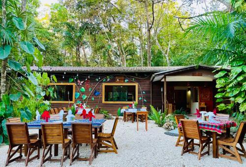 a group of tables and chairs in front of a house at Mariposa Jungle Lodge in San Ignacio