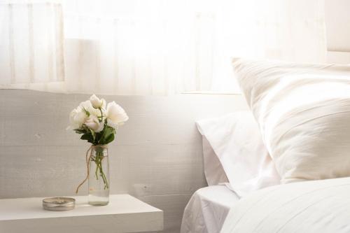 eine Vase mit weißen Blumen auf einem Tisch neben einem Bett in der Unterkunft El Bonito Salta in Salta
