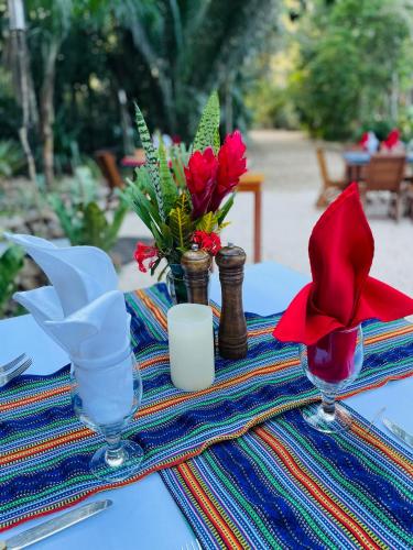 a table with two glasses and flowers on it at Mariposa Jungle Lodge in San Ignacio