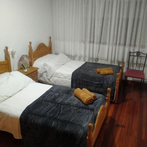 a bedroom with two beds and a red chair at A Casa da Esquina in Portomarin