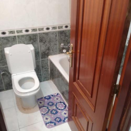 baño con aseo, bañera y puerta en A Casa da Esquina, en Portomarín