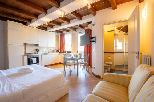 a bedroom with a bed and a table and a kitchen at Santo Stefano Apartments - BolognaRooms in Bologna