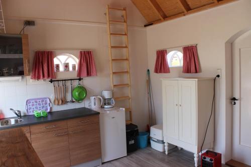 a small kitchen with a refrigerator and a sink at Trekkershuisje 't Zeeuws Knoopje in Aagtekerke