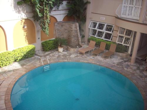 einen Pool in einem Innenhof mit Stühlen und einem Gebäude in der Unterkunft Tamareiras Park Hotel in Uberaba