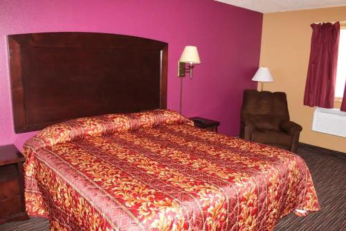 a hotel room with a bed and a chair at Coratel Inn & Suites by Jasper Stillwater in Stillwater