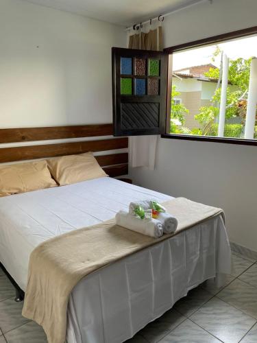 a bedroom with a bed with white sheets and a window at Chalés do Porto in Pôrto de Pedras