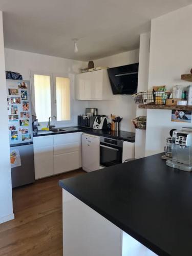 a kitchen with white cabinets and a black counter top at Appartement de charme proche de la mer in Hyères