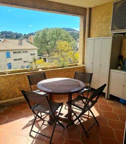 a table and chairs on a balcony with a table and a window at Appartement de charme proche de la mer in Hyères