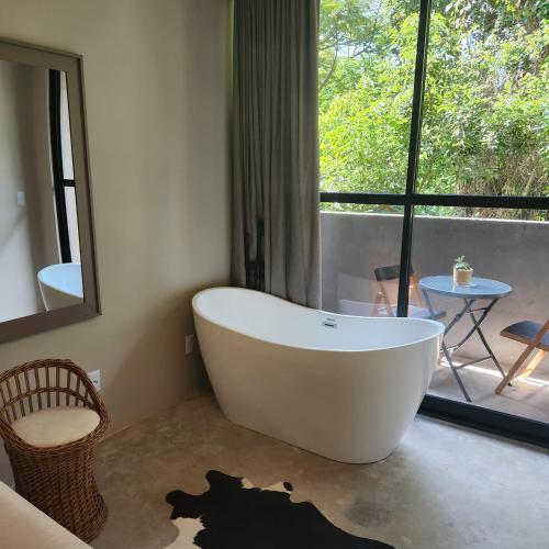 a white bath tub in a bathroom with a window at Casa Arrô - Pousada Boutique in Itajaí