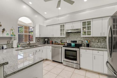 a large white kitchen with white cabinets and appliances at Cozy Beach House - 5 minutes from Vanderbilt Beach in Naples