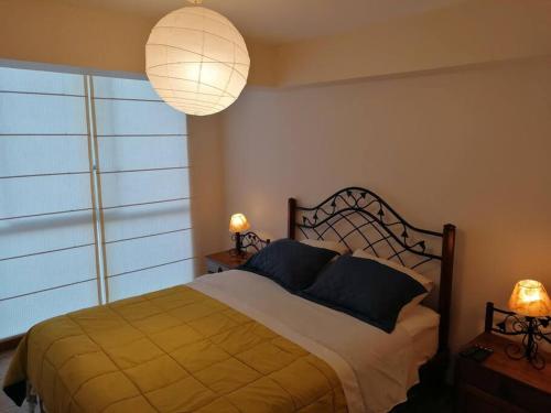 利馬的住宿－Gorgeous 2 bedroom flat in nice commercial area，一间卧室配有一张带两盏灯的床和一扇窗户。