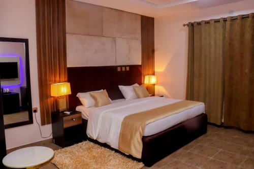 a bedroom with a large bed with two lamps and a rug at Pious Court in Port Harcourt