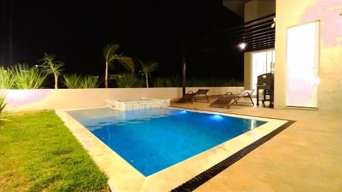 ein großer blauer Pool im Hinterhof nachts in der Unterkunft Formosa - Piscina com SPA e Poucos Passos do Clube in Palmeiras