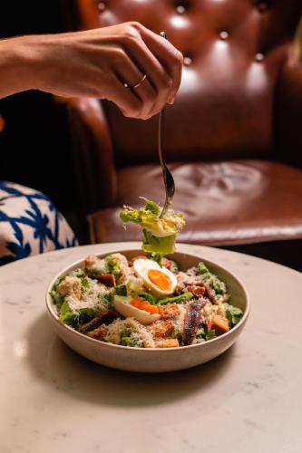 a person eating a bowl of food with a fork at The Old Clare by Ode Hotels in Sydney