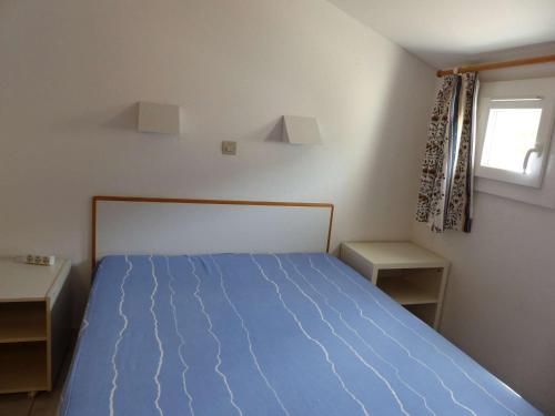 ein Schlafzimmer mit einem blauen Bett und einem Fenster in der Unterkunft Appartement Le Lavandou, 2 pièces, 4 personnes - FR-1-308-114 in Le Lavandou
