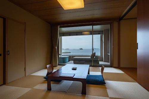 a living room with a table and a view of the ocean at IKI RETREAT by Onko Chishin in Iki
