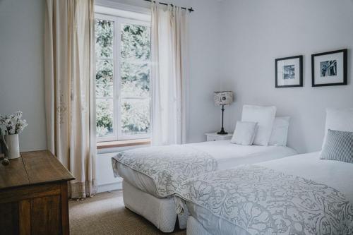 a white bedroom with two beds and a window at The French House in Trentham