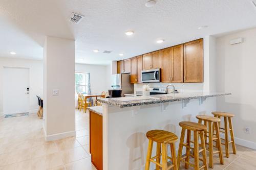 una cucina con mobili in legno e sgabelli da bar di Tropical Haven Retreat a Palm Bay