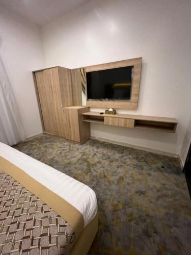 um quarto de hotel com uma grande televisão e uma cama em فندق ريسان em Al Madinah