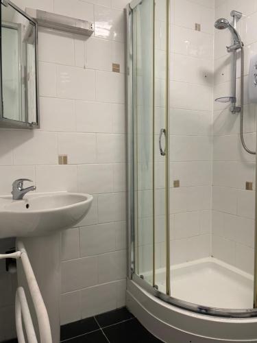 uma casa de banho branca com um lavatório e um chuveiro em Atlantic Lodge em Newquay