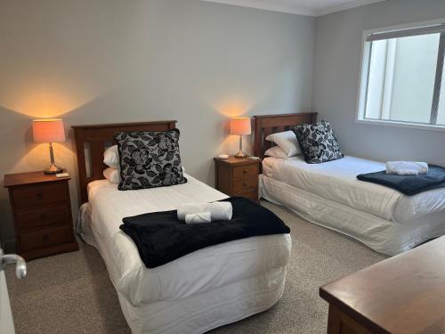 Zimmer mit 2 Betten, einem Tisch und 2 Lampen in der Unterkunft Seaside Wanaka Tce in New Plymouth